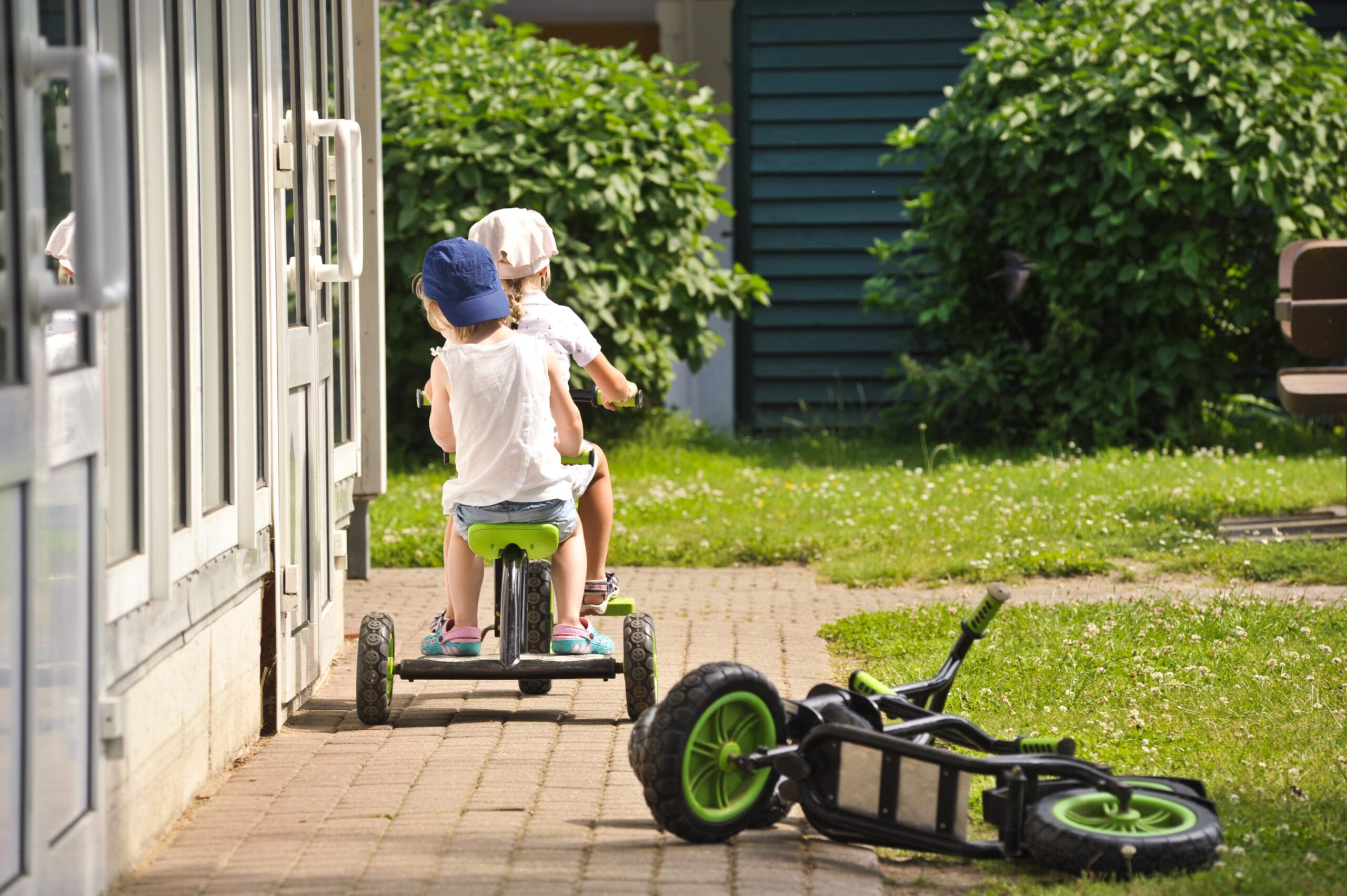 Zwei Kinder fahren auf einem Tandem-Dreirad