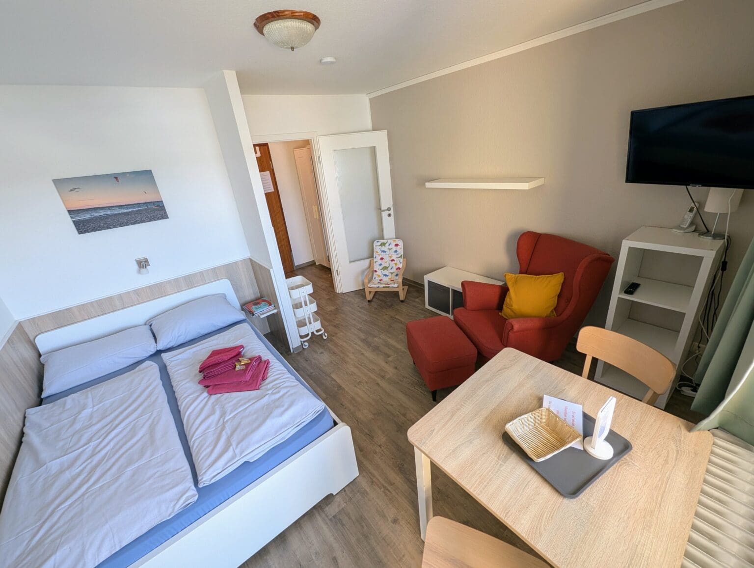 Eltern-Kind-Zimmer mit Doppelbett und rotem Sessel